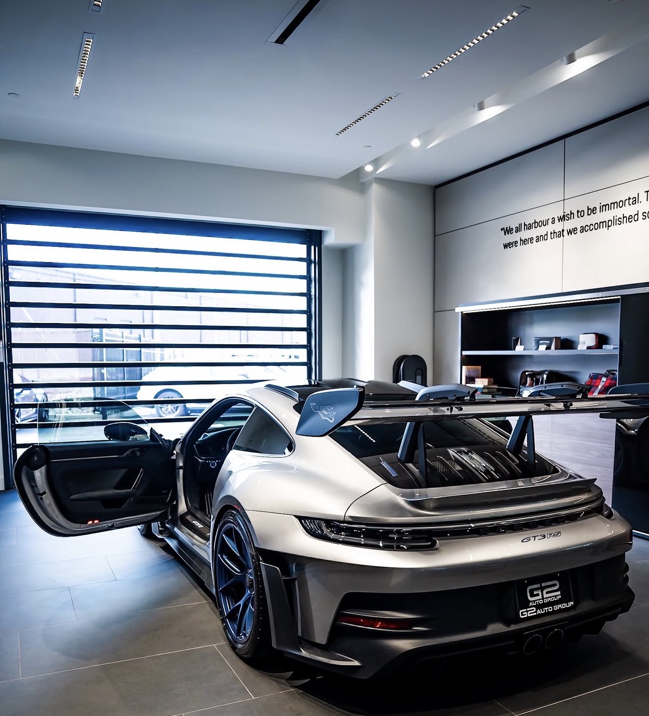 Silver Porsche 911 GT3 RS inside the G2 Auto Group showroom, driver door open